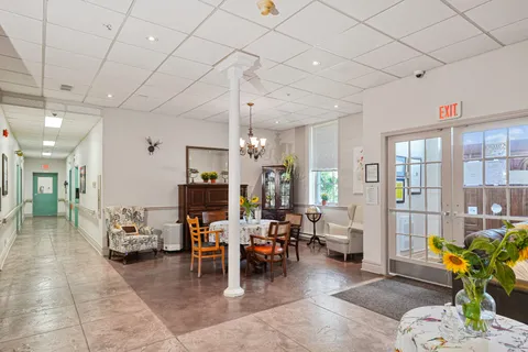 Open sitting area with armchairs, tables, a piano and glass doors