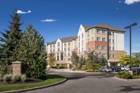 Residence exterior with a covered entrance, driveway and landscaped beds