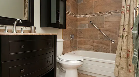 Bathroom with a bathtub, vanity and grab rails.