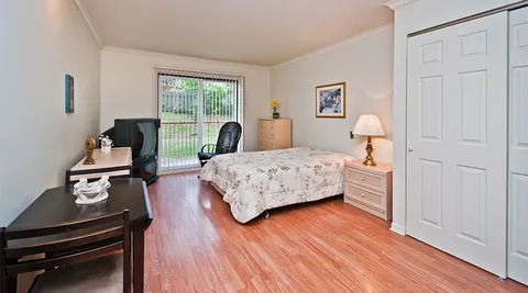 Studio suite with a bed, desk and balcony door.