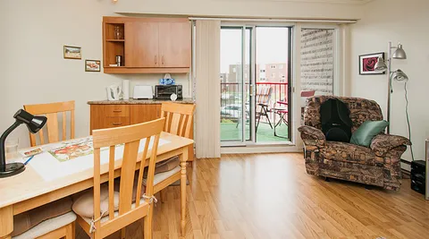 Suite kitchenette and dining table beside a balcony door.