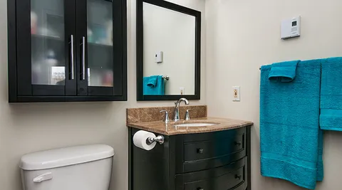 Bathroom with a dark vanity and blue towels.