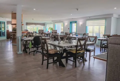 Dining room with wooden tables, chairs, large windows and ceiling lights