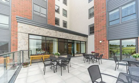 Outdoor terrace with tables, chairs and a glass railing.