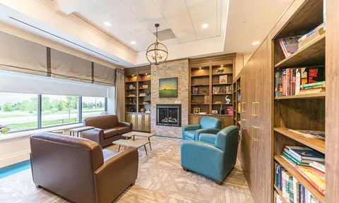 Library lounge with bookshelves, armchairs and a fireplace.