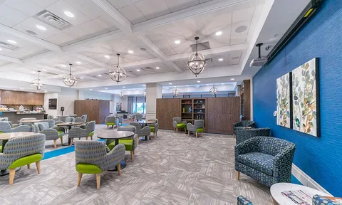 Large lounge with armchairs, tables and a blue feature wall.
