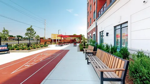 Outdoor shuffleboard court with benches and planted beds beside the residence
