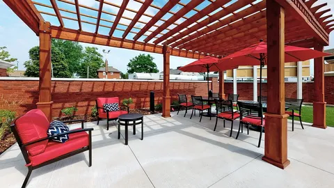 Patio beneath a wooden pergola with red umbrellas and chairs