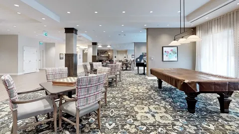 Room with a billiards table, card tables and a piano