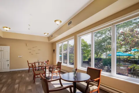 Sitting area with round tables and chairs beside large windows.
