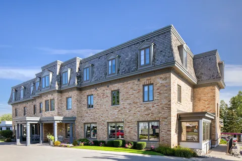 Three-storey brick residence with dormer windows and a covered entrance.