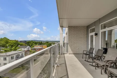 Covered balcony with metal chairs and a view over trees and neighbouring houses