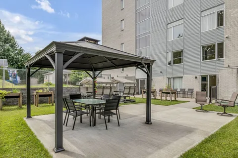 Courtyard with a gazebo, tables, chairs, covered garden swings and raised planters