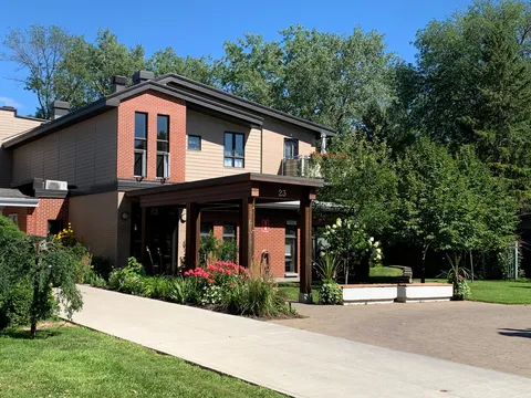 Brick and siding residence with a covered front entrance and flower beds.