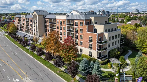Aerial view of a brick residence beside a road and landscaped gardens