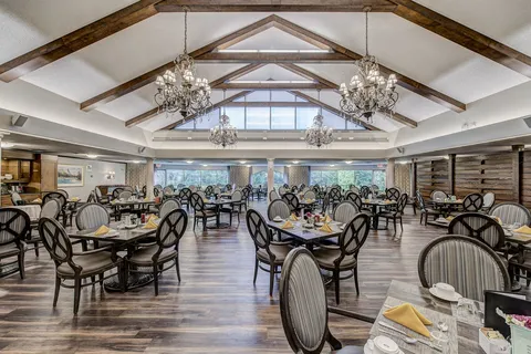 Dining room with exposed ceiling beams and chandeliers.