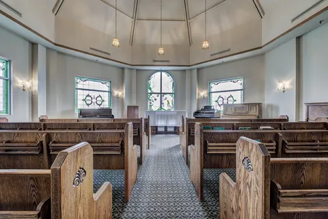 Chapel with wooden pews and windows.