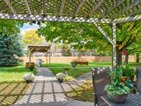 Garden path and bench beneath a pergola beside a lawn