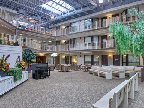 Atrium with balconies, benches, chairs and a black piano beneath a glazed roof