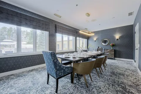 Private dining table beside large windows and blue upholstered chairs