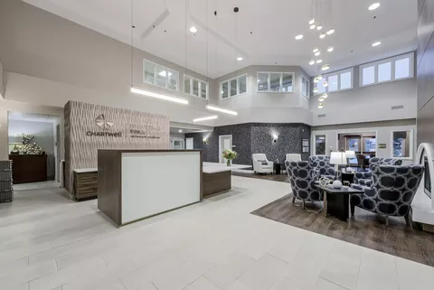 Lobby with a reception desk, patterned armchairs and high windows