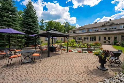 Residence building beside a paved patio with a gazebo, tables and umbrellas