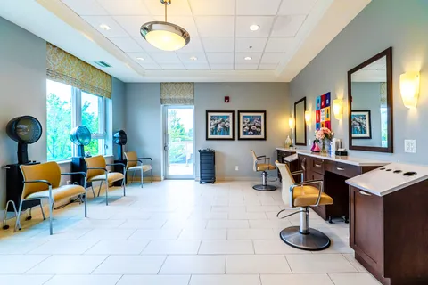 Salon with styling chairs, hair dryers, counter sinks, mirrors and framed floral pictures