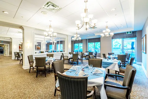Dining room with set tables, wooden chairs, chandeliers, mirrors and glass patio doors