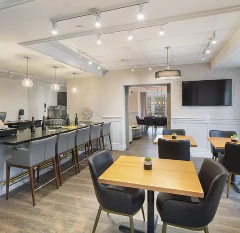 Square tables and chairs beside a counter with tall stools