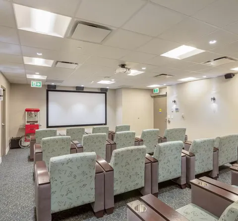 Rows of upholstered chairs facing a blank projection screen