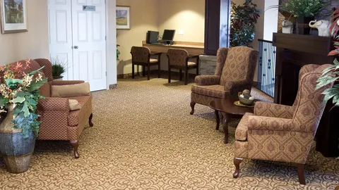 Lounge with upholstered chairs, a fireplace, plants and a computer desk.