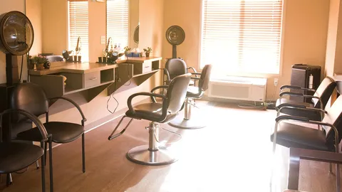 Salon with styling chairs, mirrors, hair dryers and waiting chairs.