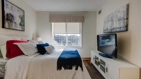 Bedroom with a bed, window, television and framed tree artwork.