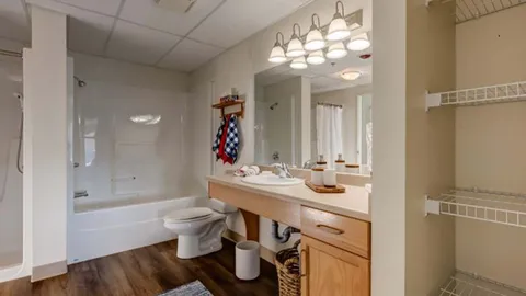 Bathroom with a bathtub, toilet, vanity mirror and open shelving.