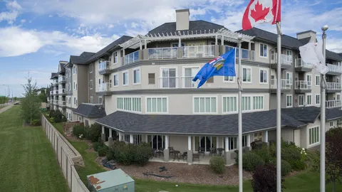 Residence exterior with balconies, a fenced lawn and flagpoles.