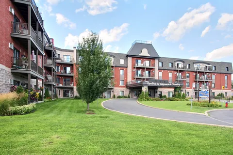 Residence buildings with balconies, lawn and a covered entrance.