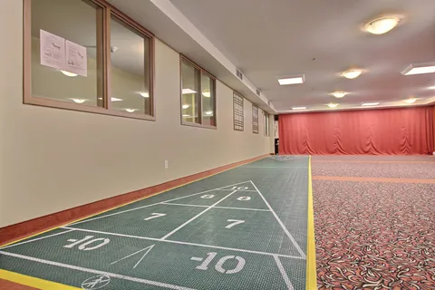 Indoor shuffleboard court beside a curtained stage.