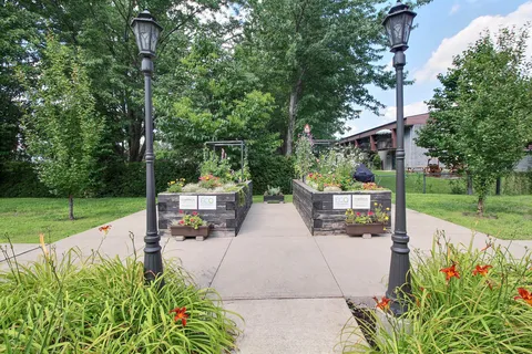 Raised garden beds and lamps beside a paved path.