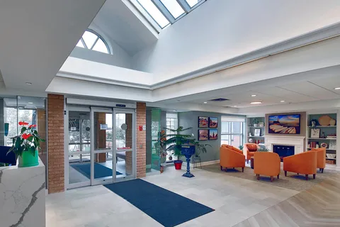 Atrium entrance with glass doors and seating beside a fireplace