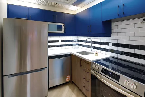 Communal kitchen with blue cabinets and stainless-steel appliances