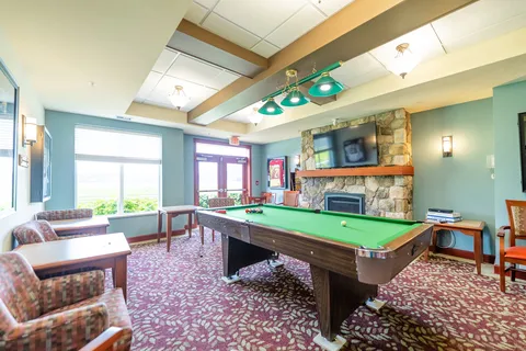 Games room with a pool table and stone fireplace.