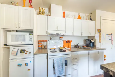 Suite kitchen with cabinets, a stove, refrigerator and sink.