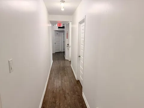 Hallway with white walls, wood flooring and doors to adjoining rooms.