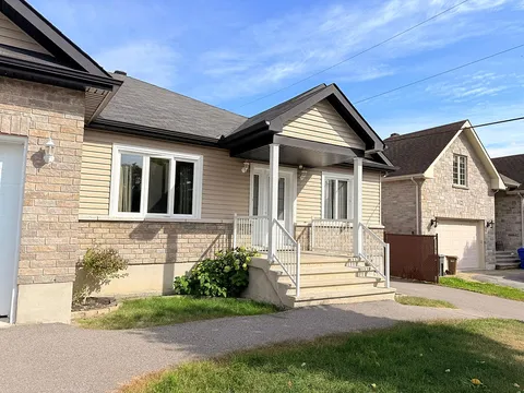 Front porch and steps with white railings beside the driveway.