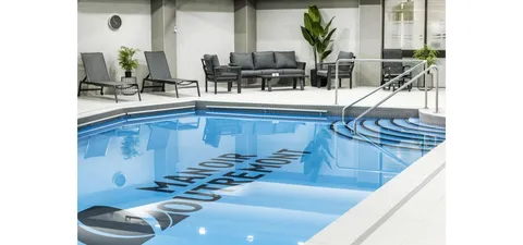 Indoor swimming pool with tiled decking and lounge chairs.