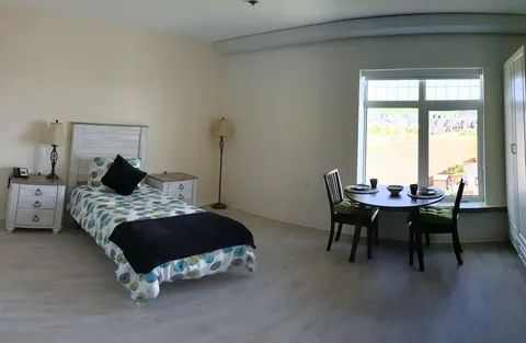 Suite with a single bed, bedside furniture and a table by the window.