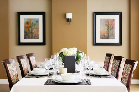 Dining table set with bowls and glasses beneath floral artwork