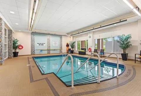 Indoor pool with metal entry rails and poolside seating.