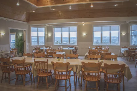 Dining room with wooden tables and chairs beneath a wood-panelled ceiling