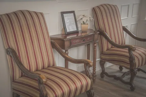 Two striped armchairs beside a side table and a potted plant